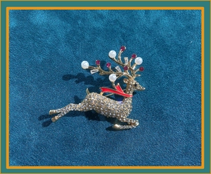Detailed view of reindeer brooch with gold plating, sparkling rhinestones and red enamel