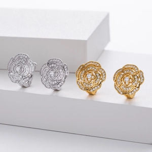 Detailed close-up of hollow camellia flower earrings in silver and gold with pavé cubic zirconia