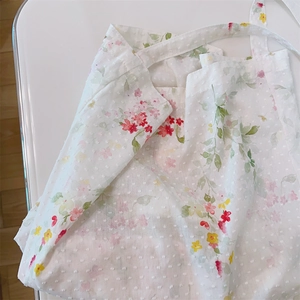 Detailed macro view of Swiss dot cotton fabric with floral patterns and matching lace ties