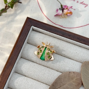 Detailed close-up of a gold ladybug brooch with green crystals in a vintage jewelry box