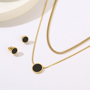 Detail of double-layer gold snake chain necklace and stud earrings with black shell inlay