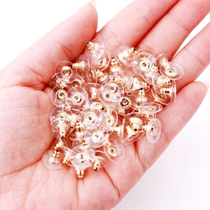 Golden earring backings with clear plastic safety pads displayed on a palm