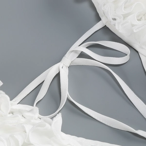 Nahaufnahme eines weißen Rückenfreien Chiffonkleides mit Rüschen und Schnürung