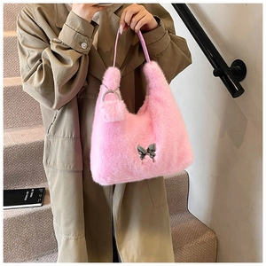 Pink plush saddle bag with silver butterfly buckle held by a model in a trench coat