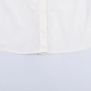 Close-up of a white poplin shirt featuring a curved hem and premium stitching detail