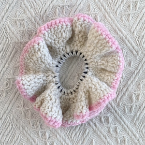 Close-up of handmade cream crochet scrunchie with pink wavy ruffled edge detail