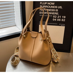 Detail of camel bucket bag with lychee leather, gold studs and ethnic woven strap