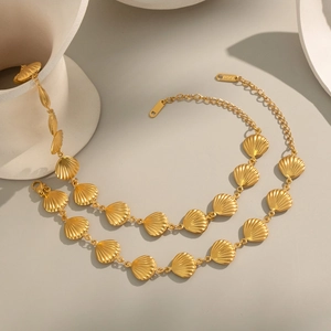 Dettaglio collana con conchiglie placcata oro 18K con pendenti a ventaglio su sfondo beige