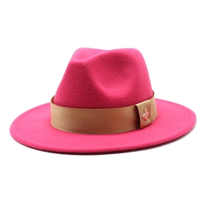 Detail of rose red wool fedora hat featuring a khaki ribbon and golden bee buckle