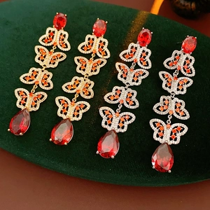 Détails de boucles d'oreilles papillon vintage avec zircons rouges sur plateau velours