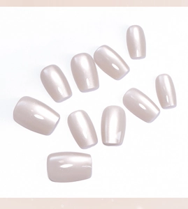 Détail de faux ongles œil de chat champagne avec éclat perlé et forme carrée arrondie