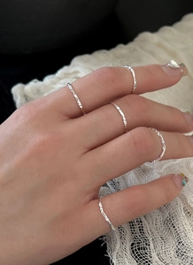 Macro detail of minimalist S925 sterling silver rings with hammered texture on model hand