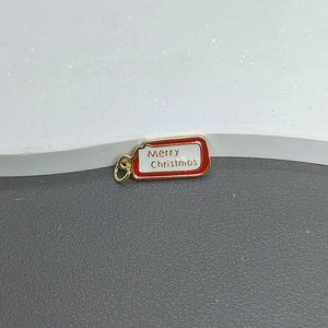 Close-up of golden Merry Christmas pendant with red enamel and micro-pave zircon detail