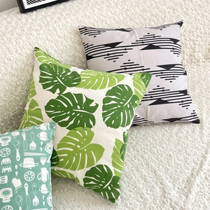 Three square cotton linen cushion covers with leaf and geometric prints on white fur rug