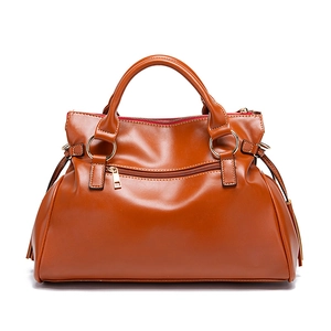 Vista frontal detallada del bolso vintage de cuero suave marrón con borla y oro