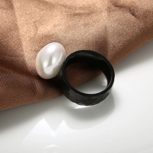 Macro shot of a hammered black stainless steel ring featuring a baroque white pearl detail
