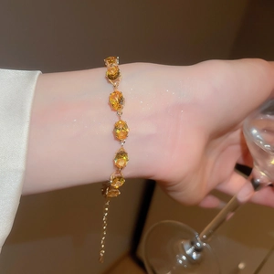 Elegant gold bracelet featuring oval yellow gemstones with an adjustable chain on wrist
