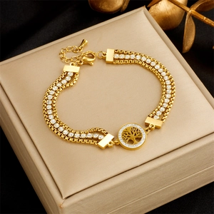 Detailed close-up of a gold multi-layer bracelet with tree of life and zircon charms