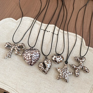Macro view of leopard print pendants featuring heart, star, and bow designs on black cord