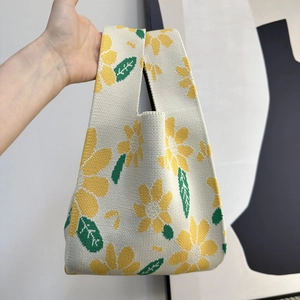 Close-up of knit tote bag featuring yellow sunflower patterns and green leaves