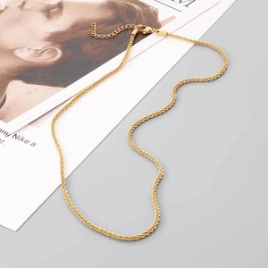 Vue détaillée d'un collier en chaîne torsadée en acier doré sur un support carte