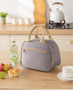 Close-up of lilac insulated lunch bag with gold TASTY FOOD text and brown handles