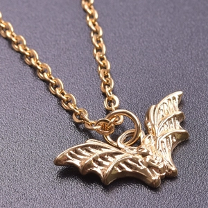 Macro shot of 18K gold bat pendant featuring fine metal texture and sleek link chain