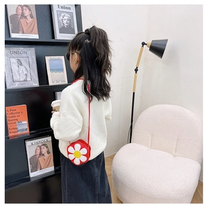 Cute red and white daisy flower crossbody bag for kids displayed on a modern white sofa