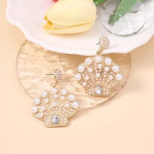Detailed view of golden shell earrings with inlaid pearls and teardrop gemstones