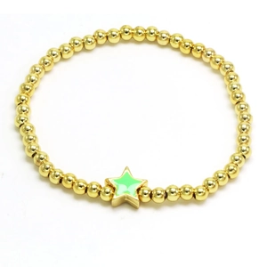 Macro detail of golden beaded bracelet featuring a green star pendant on white background