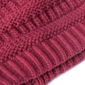 Close-up of thick burgundy knitted beanie showing warm cable knit texture
