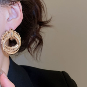 Detailed close-up of layered golden geometric earrings with mixed matte and polished finish