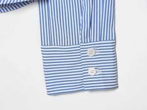 Detailed macro view of the blue and white striped shirt cuff with two white buttons
