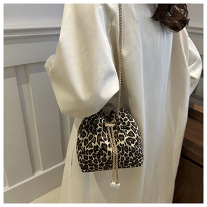 Close-up of leopard bucket bag with golden chain strap and pearl drawstring detail