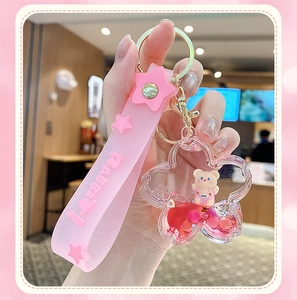 Detailed view of pink liquid sand keychain with rabbit strap and mini bear figurine