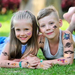 Space themed temporary tattoos showing rockets and planets on kids playing on grass