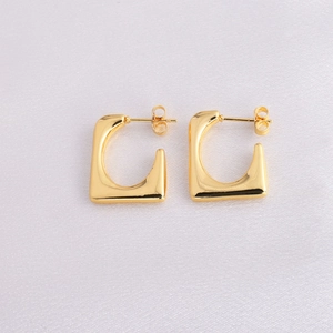 Detailed view of gold rectangular hoop earrings on soft fabric background with secure backs