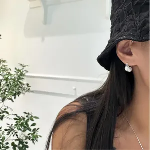 Close-up of a model wearing minimalist silver water drop hoop earrings with glossy finish