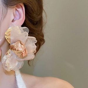 Detail of pink chiffon fabric flower earrings with textured gold metal accents on a model