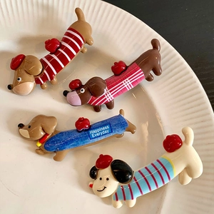 Cute dachshund hair clips in four colorful patterns displayed on a white ceramic plate