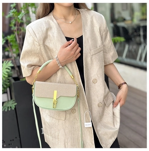 Detail of mint green crossbody box bag with beige woven flap and gold metal lock