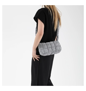 Detailed side view of a gray quilted puffy shoulder bag on a model for modern style