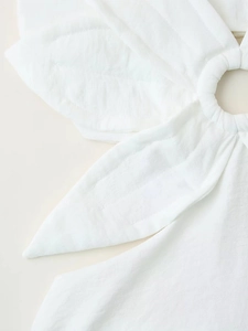 Détail de robe blanche avec fermoir en anneau métallique et texture plissée élégante