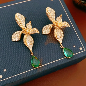 Detail shot of vintage gold flower earrings with green pear-shaped drop stones
