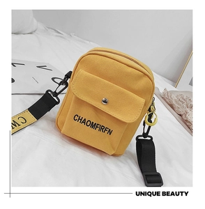 Close-up of yellow canvas crossbody bag featuring front pocket and black woven strap detail