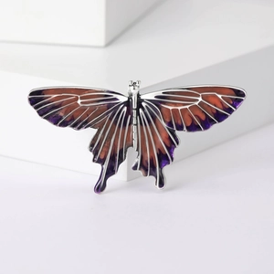 Detailed view of an alloy butterfly brooch with purple and orange gradient enamel wings