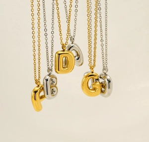 Detail of 3D bubble initial necklaces in gold and silver finish with high polished surface