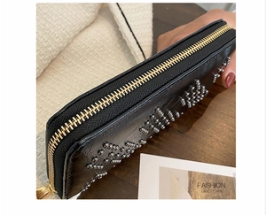 Detail der schwarzen Leder-Clutch mit silbernen Nieten und goldenem Metallreißverschluss