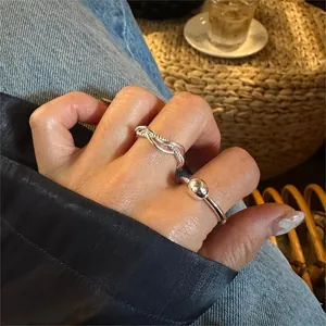 Detail of twisted rope ring and beaded silver band worn in a casual lifestyle setting
