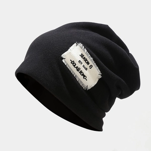 Close-up of black knitted beanie with SEASON B EST 2008 patch showing fabric texture